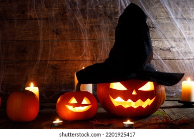 Festive mystical halloween interior. Pumpkin, spider web, burning candles, spiders on dark wooden background - Shutterstock ID 2201925417