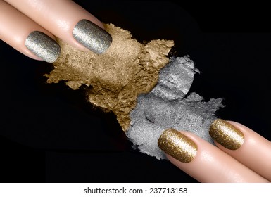 Festive Nail Art. Fingers With Trendy Gold And Silver Nail Polish And Crushed Eye Shadow With Drops Of Water. Manicure And Makeup Concept. Closeup Image Isolated On Black