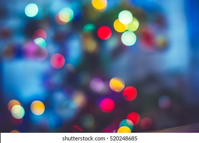 Festive New-year background with bokeh from Christmas tree lights glowing. Blurred colorful circles on light holiday background