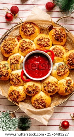 Festive parmesan garlic bread in a wraith shape around tomato dip served on a table, top view with some Christmas tree red ornaments
