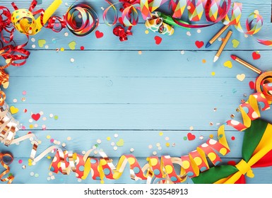 Festive party border or frame of colorful spiral streamers and confetti arranged on a rustic old blue wooden background with a bow tie in the corner and copyspace