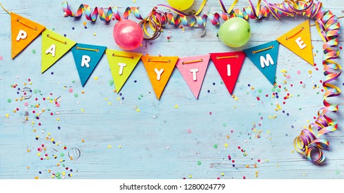 Festive Party Time banner with copy space and a border of colorful triangular bunting , streamers and balloons around blue wood with confetti - Shutterstock ID 1280024779