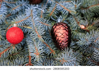 Festive pine tree branches adorned with red and bronze christmas ornaments.