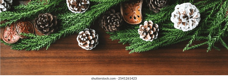 Festive pinecones and evergreen branches on a wooden table. Pinecones and greenery create a holiday feel. Pinecones add a rustic touch to the decor. Christmas and winter decorations with copy space. - Powered by Shutterstock