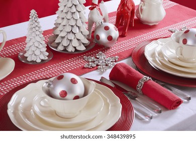 Festive Red And White Christmas Table Setting With Fine China Place Setting, Reindeers And Holiday Ornaments And Decorations, Closeup.