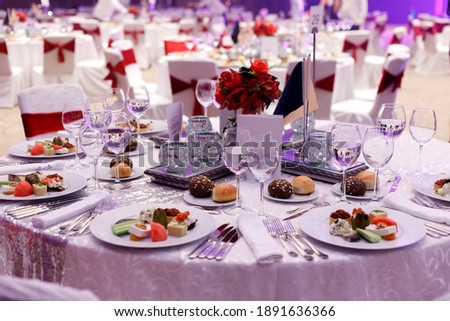 Festive round table setting in a prestigious restaurant for dinner. Banquet decoration with white and red