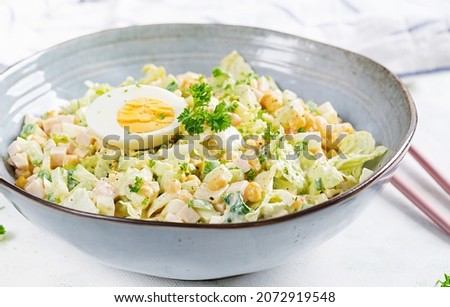 Festive salad with ham, cucumber, boiled eggs, sweet corn and mayonnaise on rustic.