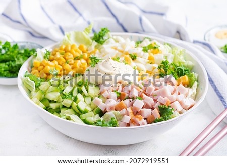 Festive salad with ham, cucumber, boiled eggs, sweet corn and mayonnaise on rustic.