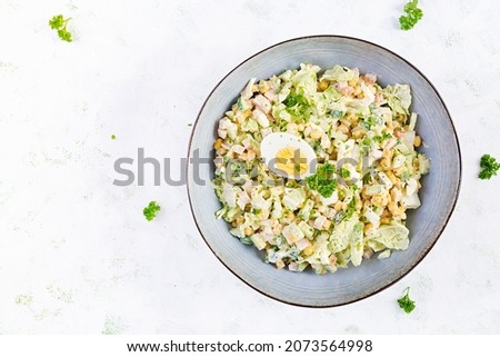 Festive salad with ham, cucumber, boiled eggs, sweet corn and mayonnaise on rustic. Top view, above