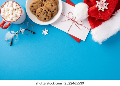 A festive scene featuring cookies, hot chocolate with marshmallows, Santa hat, and a holiday envelope on a blue background - Powered by Shutterstock