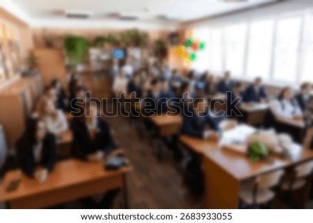 Festive school classroom interior with students in formal uniform sitting at wooden desks during holiday lesson, decorated with colorful balloons, flowers and bright natural sunlight