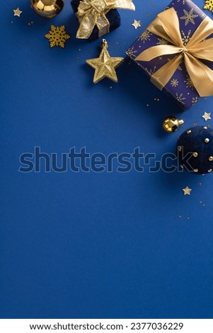 Festive season gifts. Overhead vertical shot of glistening blue and gold-wrapped presents, ornaments, star accent, snowflake, sequins on an opulent blue backdrop with room for greetings or ad