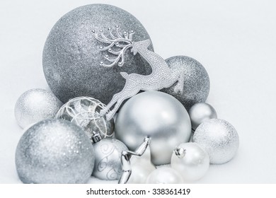 Festive silver grey shiny Christmas ornaments with Santa's ninth reindeer at natural white snow background