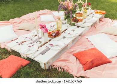 Festive Summer Picnic In The Garden With Tasty Food, Fruits, White Wine And Beautiful Flowers For Friends Or Family. Birthday Or Wedding Celebration. Hen-party. Leisure And Rest