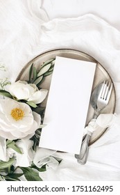 Festive Summer Wedding Scene. Marble Table Setting With Cutlery, Olive Branches, White Peony Flowers, Stoneware Plate And Silk Ribbon. Blank Restaurant Menu Card Mockup. Flat Lay, Top View, Vertical.