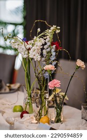 Festive table decorated with composition of red, pink flowers and greenery, candles in hall. Table newlyweds and guest in banquet area on wedding party. Luxurious celebration of event in restaurant.