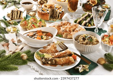 Festive table with fried carp, mushroom soup, sauerkraut, puff pastry pies, herrings, salads and pastries for traditional Polish Christmas Eve's supper 