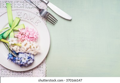 Festive Table Place Setting With Hyacinths Flowers Decoration, Plate, Fork And Knife On Light Green Background, Top View. Spring Or Easter Food.