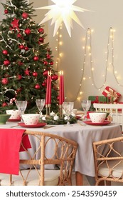 Festive table setting with burning candles and Christmas decorations in dining room
