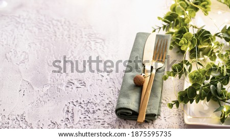 Festive table setting with ceramic plate, gold cutlery , garland and eucalypt brunch. Merry Christmas and Happy New Year celebration concept. 