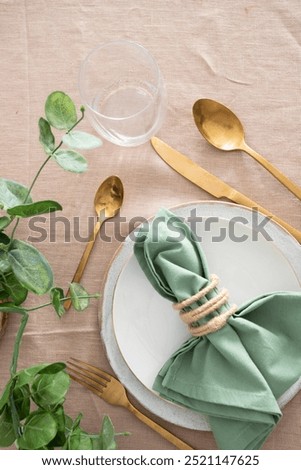Festive Table setting for elegant dinner with white porcelain plates, glass, green napkin, gold cutlery and centre place. Copy space