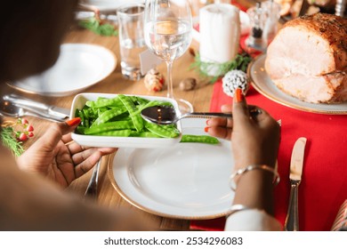 Festive table setting with a focus on green beans. A person serves green beans, highlighting a holiday meal. Green beans add a fresh touch to the festive table.