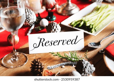 Festive table setting with a 'Reserved' sign. Holiday decor and pine cones on wooden table. Reserved sign on wooden table with Christmas decorations - Powered by Shutterstock