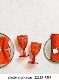 Festive Table Setting For Valentines Day With Red Glass Colored Wine Glasses, Trendy Plates, Linen Napkins On Table, Copy Space, Flat Lay. Concept Holiday Home Dinner 14 February, Vertical Format