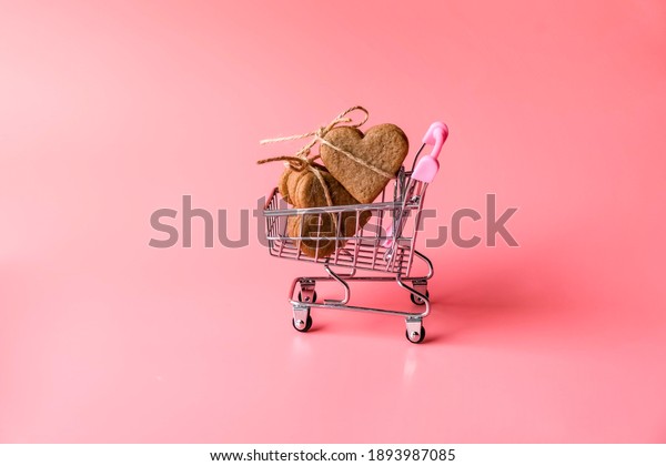 festive\
valentine\'s day holiday flat lay. annual holiday shopping concept\
and \
reasonable consumption.Cookies form of heatrs tied jute rope\
on shopping basket on pink background. Zero\
waste