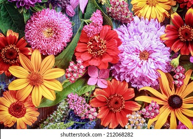Festive vibrant floral background with a large arrangement of colorful summer flowers in rainbow colors including dahlias and gerbera daisies for celebrating a special occasion or holiday