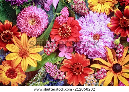 Festive vibrant floral background with a large arrangement of colorful summer flowers in rainbow colors including dahlias and gerbera daisies for celebrating a special occasion or holiday