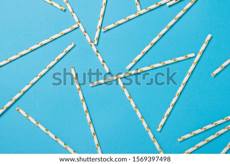 Festive white with gold drinking straws on a blue background. Holiday concept, decoration. Flat lay, top view