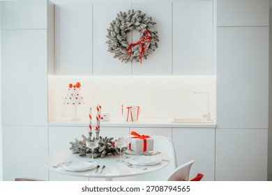 Festive white kitchen table setting with Christmas wreath candles and gifts