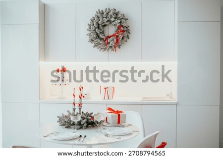 Festive white kitchen table setting with Christmas wreath candles and gifts