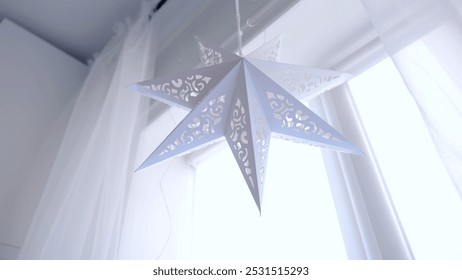 Festive white paper star hangs in a bright room, creating a cozy and warm atmosphere, evoking joy, love, and childhood holiday memories. A day with family before Christmas. New Year's Eve with family - Powered by Shutterstock