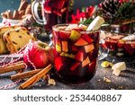 Festive winter fruit punch or sangria drink. Christmas mulled red wine. Ponche de frutas Navideño cocktail, Mexian Christmas hot  beverage with sugar cane and fruit, hot sweet liquor wine drink