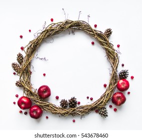 Festive wreath of grape vines decorated with apples, cranberries and cones. Wedding, birthday, Valentine's day concept. Beautiful DIY natural wreath on white background. Flat lay, top view