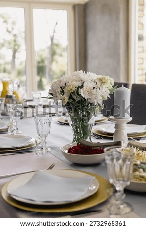 Festively decorated dining table with tableware, glasses, flowers and candles. Festive dining table decorated with elegant tableware, glasses, flowers and candles prepared for celebration or special event. Holiday decor, dinner party and elegant table setting concept.