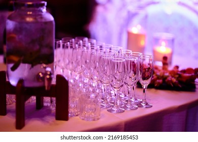 festively served table, many empty glasses for alcohol stand on the table, purple light