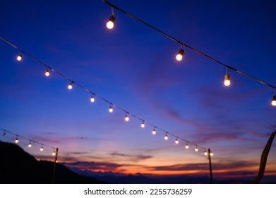 Festoon string lights decoration at the party event festival against sunset sky. light bulbs on string wire with copy space. Outdoor holiday background - Powered by Shutterstock