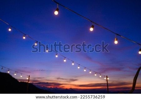 Festoon string lights decoration at the party event festival against sunset sky. light bulbs on string wire with copy space. Outdoor holiday background