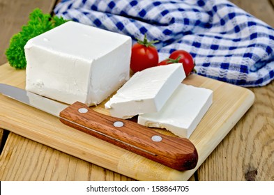 Feta cheese, knife, parsley, tomatoes, napkin on a wooden board - Powered by Shutterstock