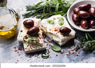 Feta cheese with olives and green herbs on gray marble background - Shutterstock ID 255256354