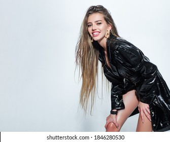 Fetish Fashion. Young Pretty Woman With Sexy Slim Body And Long Hair, Erotic Black Latex Coat On White. Smiling Young Woman Face, Happy Girl. Portrait Of Seductive Elegant Young Woman