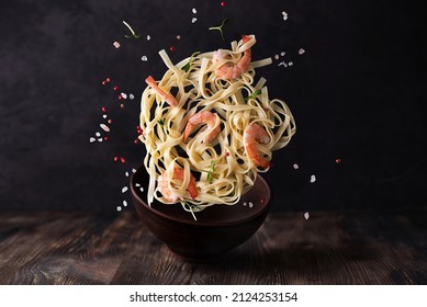 Fettuccine and prawns on dark wooden background, levitating pasta with shrimps and spices. - Shutterstock ID 2124253154