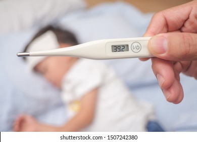 Fever, Close-up medical thermometer, Parent / Father measuring temperature of his ill kid, Asian 3 - 4 years old toddler boy gets high fever lying on bed with cold compress on forehead to cool a fever - Shutterstock ID 1507242380