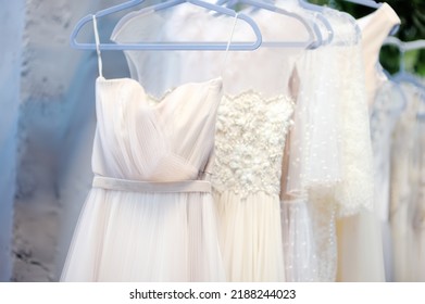Few beautiful dresses on hanger in wedding salon or atelier sewing studio. Wedding exhibition or shop, evening and bridesmaid dresses. Holiday and events clothes rental. Personal sewing clothes