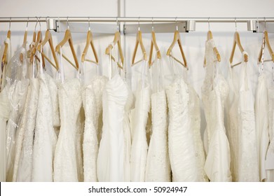 A Few Beautiful Wedding Dresses Hanging On The Stand