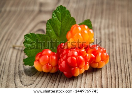 few berries of cloudberries with a leaf on an old wooden board close-up