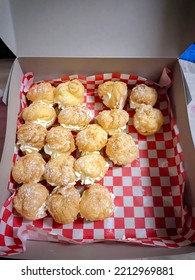 A Few Creampuff Cookies In A Box Lined With Red And White Paper.